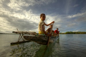 Children on a outrigger canoe in the village of Hessessai Bay at PanaTinai (Panatinane)island in the Louisiade Archipelago in Milne Bay Province, Papua New Guinea.  The island has an area of 78 km2.