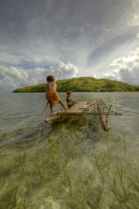 Children playing with a outrigger canoe in the village of Hessessai Bay at PanaTinai (Panatinane)island in the Louisiade Archipelago in Milne Bay Province, Papua New Guinea.  The island has an area of 78 km2.